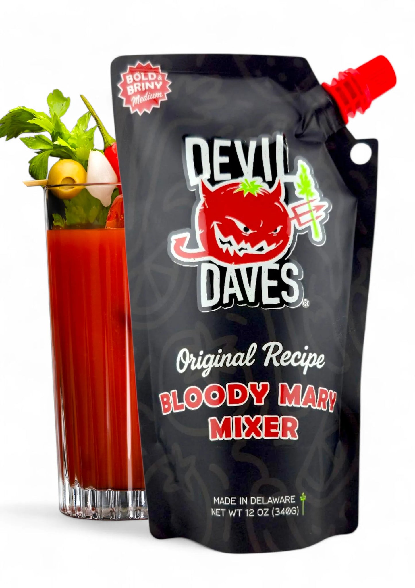 A 12 oz pouch of Bloody Mary mix next to glass on white background
