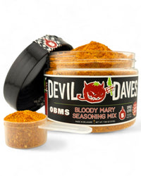 A container of Devil Daves Bloody Mary Seasoning Mix with a white spoon inside, showing the granular seasoning.